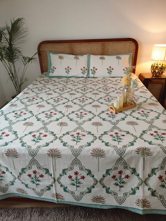 Bed with floral patterned bedsheet and matching pillows in a bedroom setting.