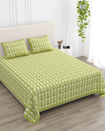 Harsingar Green bedsheet, leaf-green ground with rows of white flowering stems, in a studio shot against a cream headboard