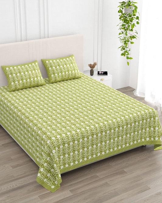 Harsingar Green bedsheet, leaf-green ground with rows of white flowering stems, in a studio shot against a cream headboard