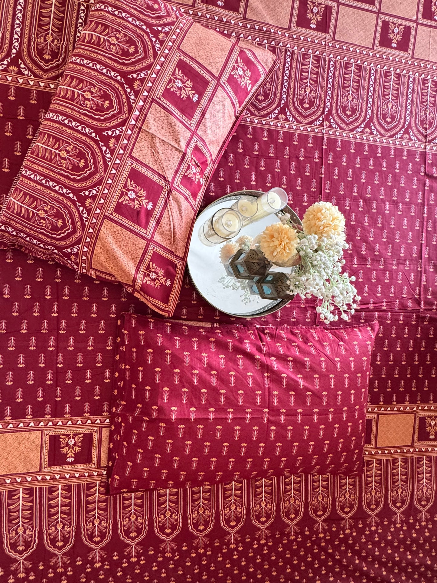 Close-up of Tarang Red bedsheet and pillow cover with a tray of flowers