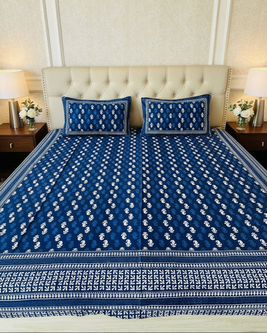 Blue and white patterned bedspread on a bed with matching pillows.