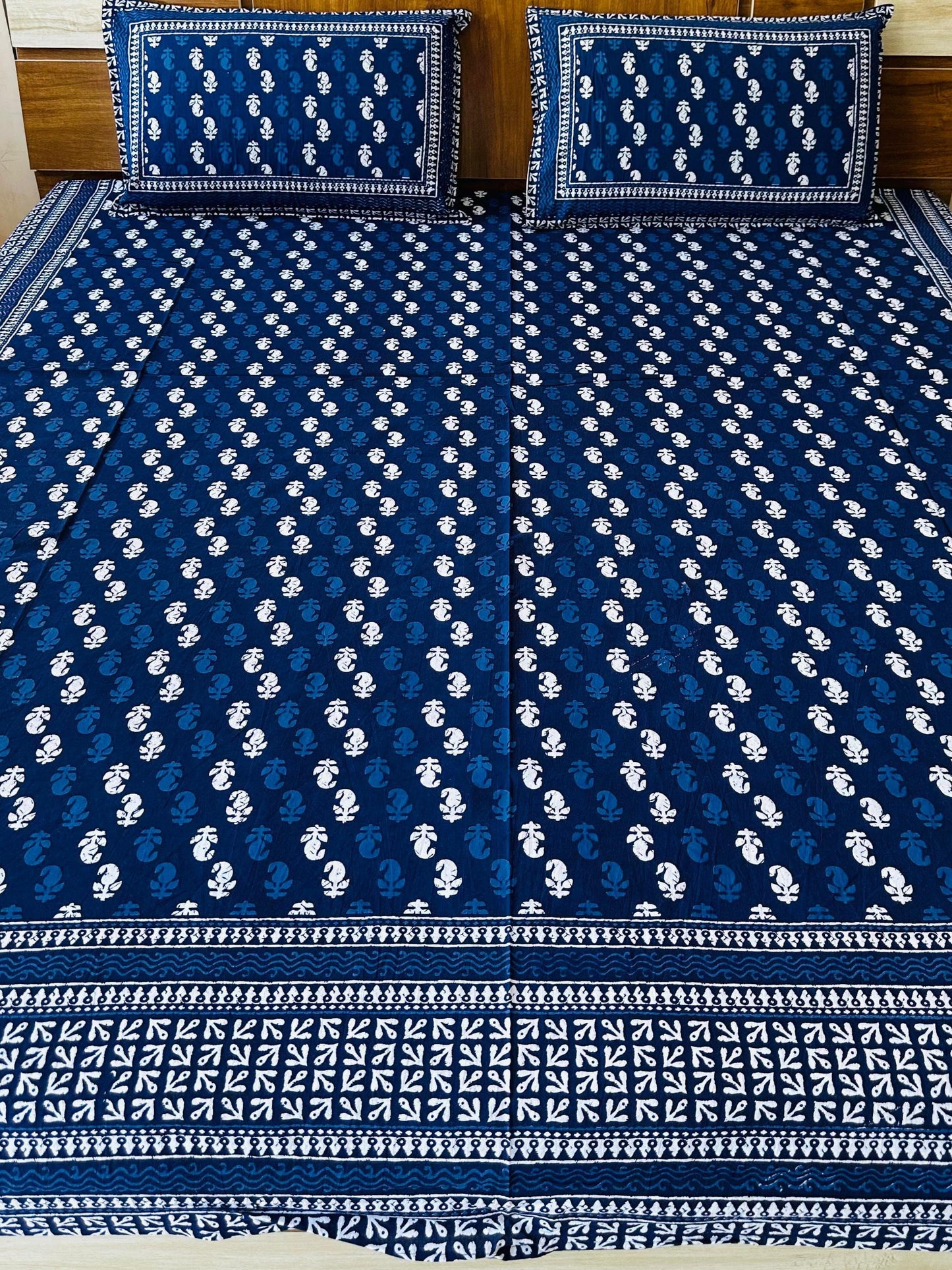 Blue and white patterned bedspread on a bed with matching pillows.