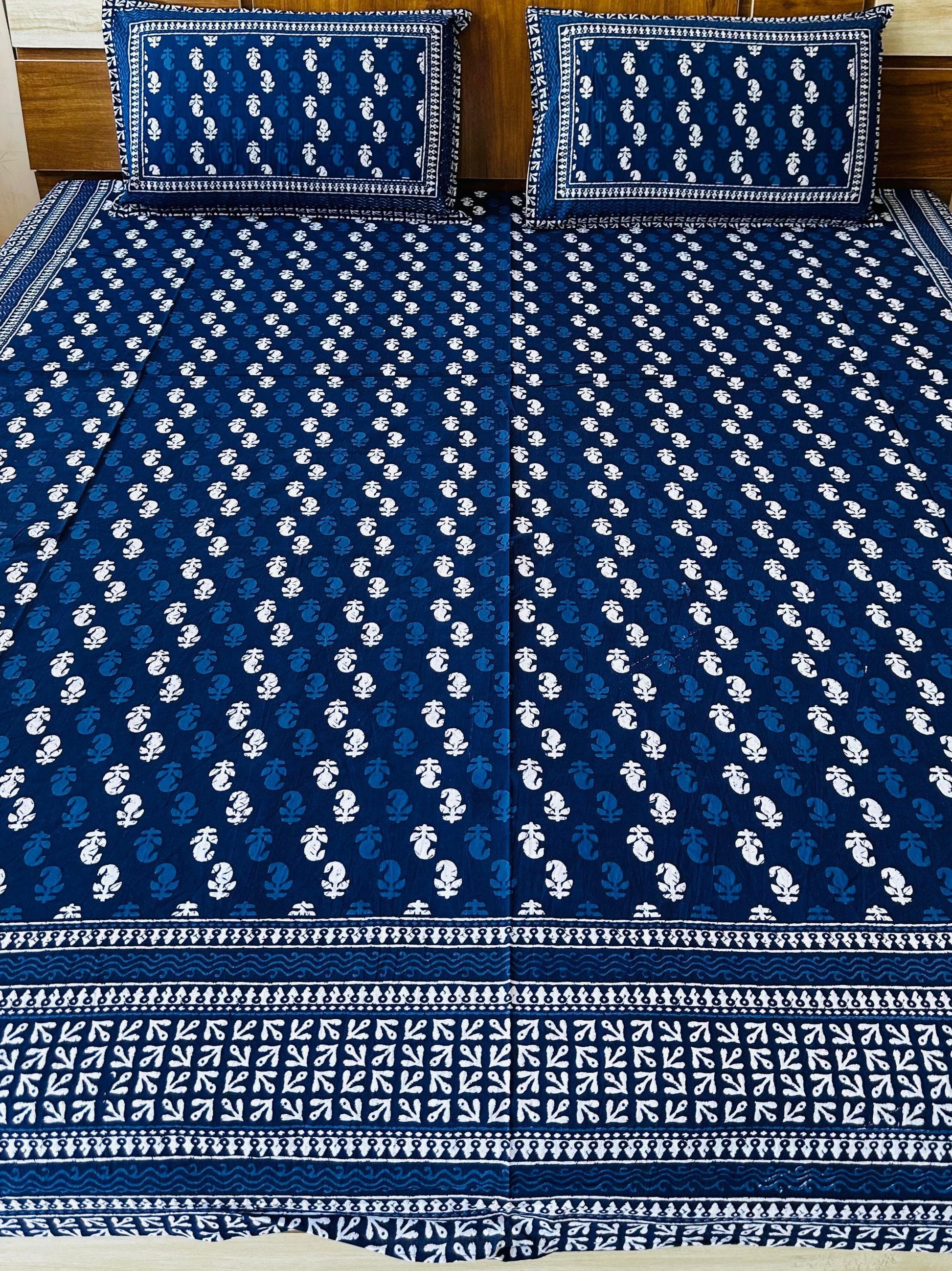 Blue and white patterned bedspread on a bed with matching pillows.