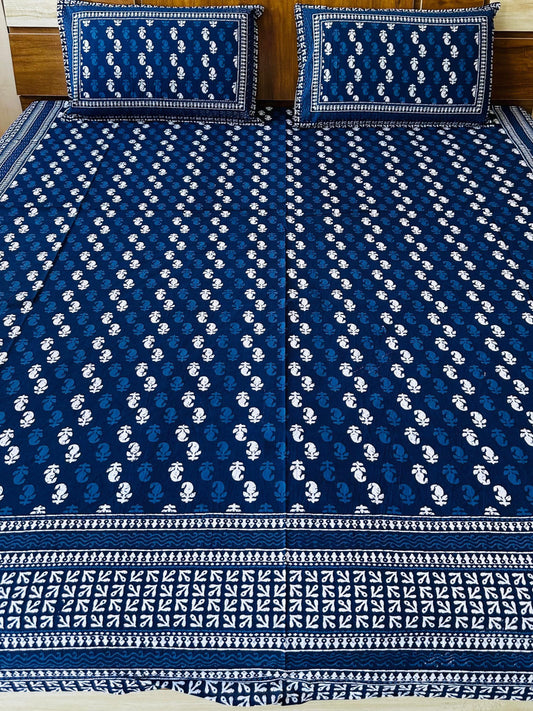 Blue and white patterned bedspread on a bed with matching pillows.
