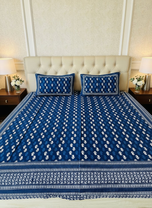 Blue and white patterned bedspread on a bed with matching pillows.