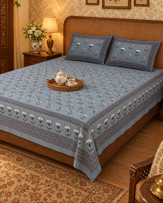 Japaa Blue bedsheet with rows of ivory buta and a patterned border, with a tea tray on a cane-headboard bed