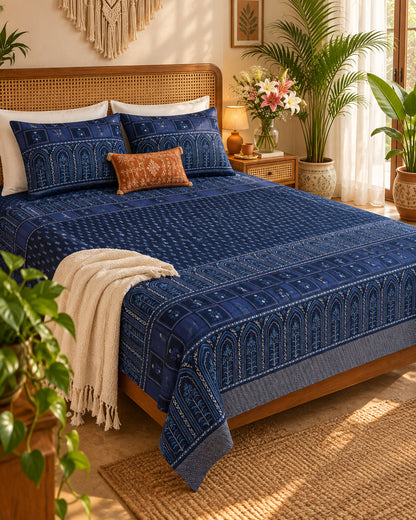 Tarang Blue bedsheet styled with a rust cushion and cream throw on a wooden bed
