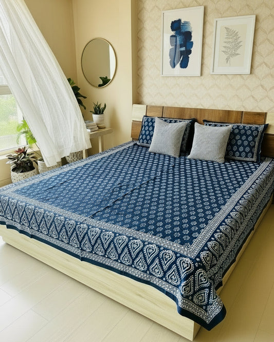 Navy blue and white patterned bedspread on a bed with matching pillows.