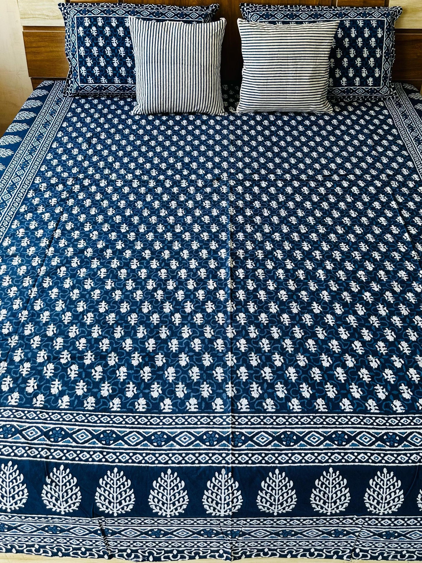 Bed with blue and white patterned bedspread and pillows in a room.