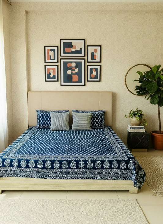 Bed with blue and white patterned bedspread and pillows in a room.