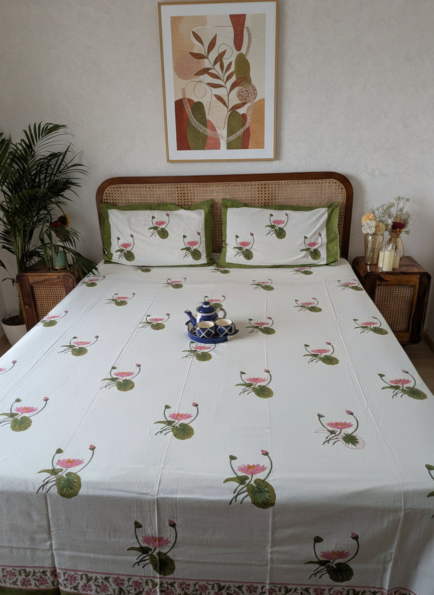 Bed with floral patterned bedsheet and pillows with lotus motif in a room setting.