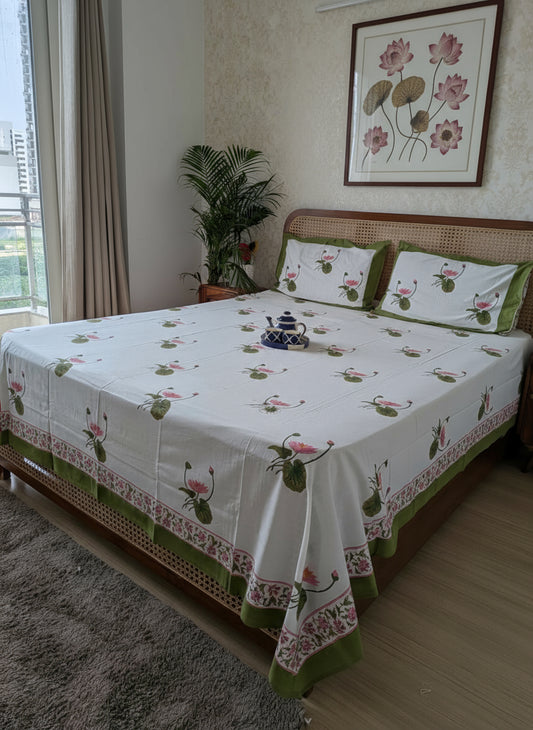 Bedroom with a bed covered in a floral-patterned bedsheet, pillows with lotus motifs.