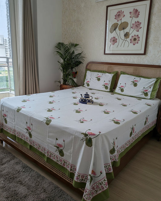 Bedroom with a bed covered in a floral-patterned bedsheet, pillows with lotus motifs.