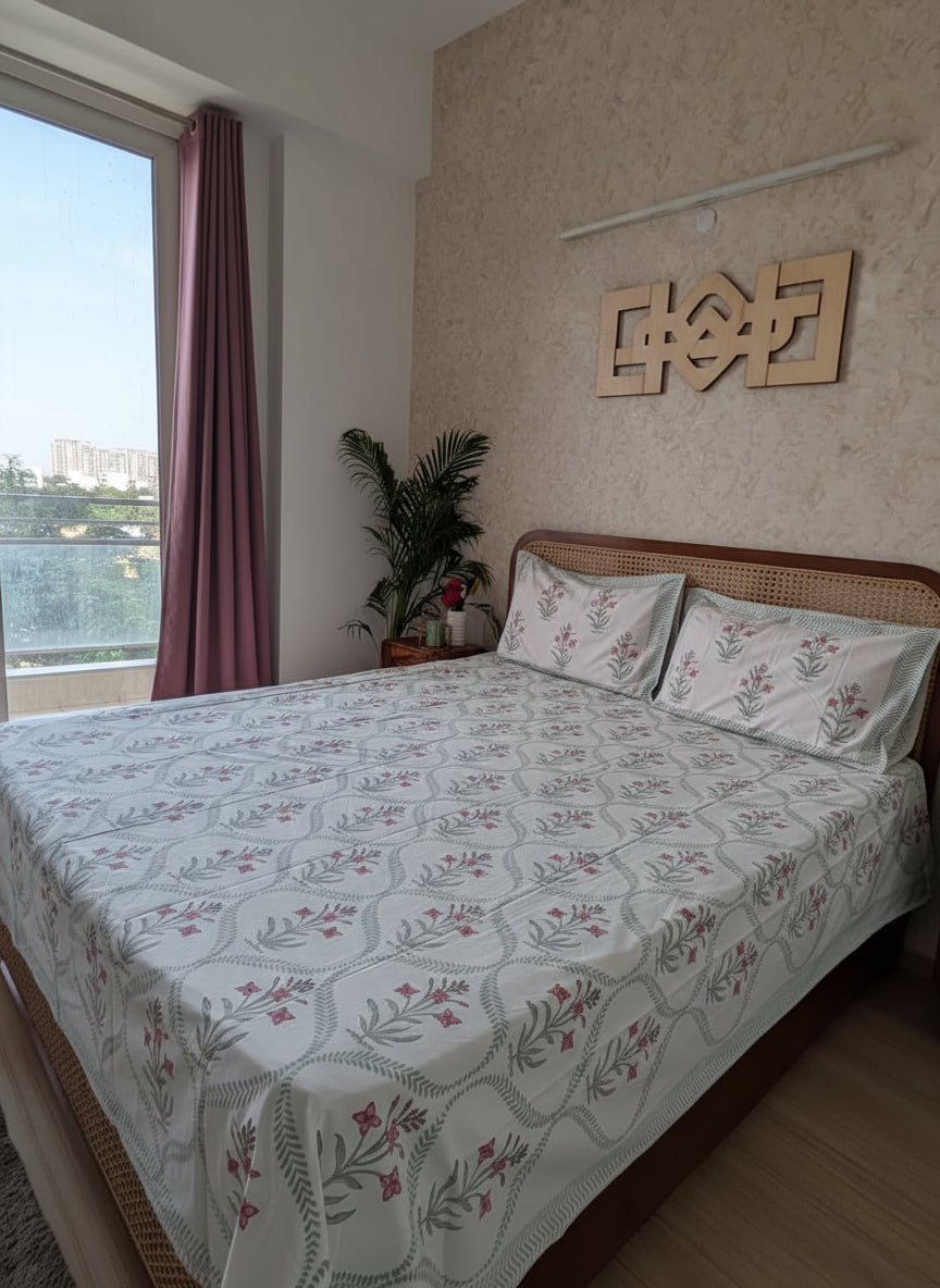 Bedroom with floral-patterned bedspread and a view of a cityscape from a window.