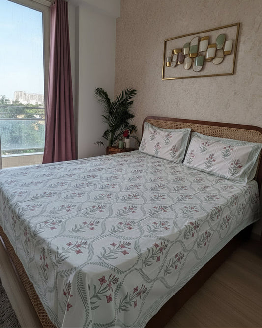 Bedroom with floral-patterned bedspread and a view of a cityscape from a window.