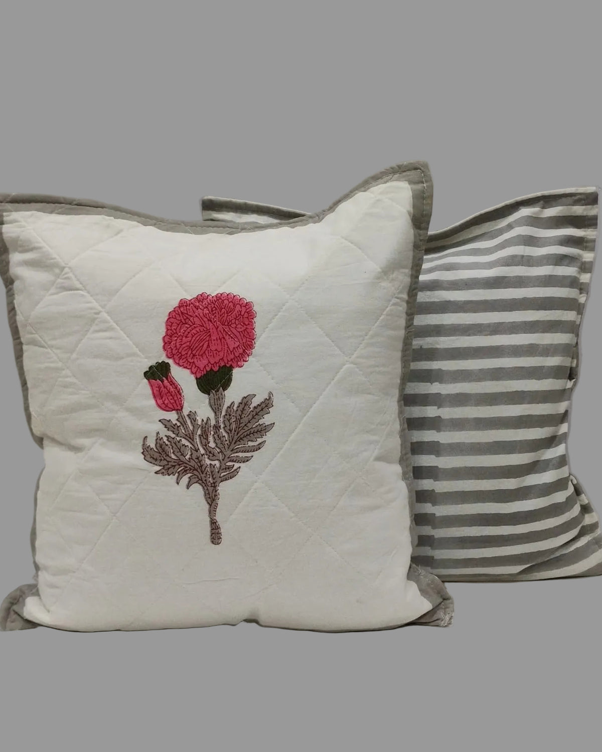 Kesariya grey quilted cushion cover shown beside its grey striped reverse