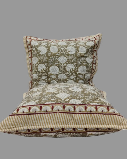 Two Kumud beige quilted cushion covers stacked to show the floral print and striped reverse