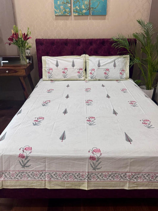 Bed with floral bedspread and pillows in a bedroom setting