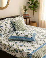 Latika blue and green floral cotton bedsheet styled with a green dotted cushion and blue-bordered pillow cover