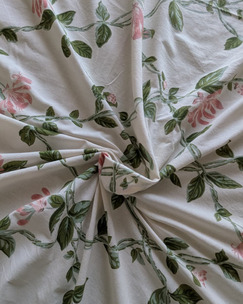 Floral patterned fabric with pink flowers and green leaves on a white background