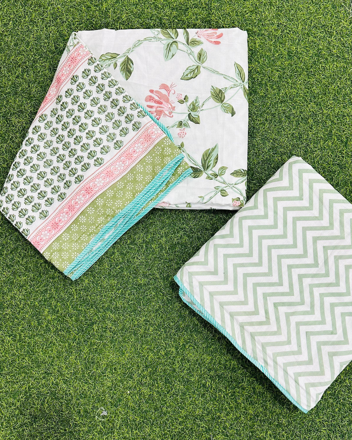 Reversible pink and green floral mulmul dohar folded to show the printed side and the chevron reverse