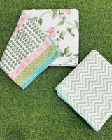 Reversible pink and green floral mulmul dohar folded to show the printed side and the chevron reverse