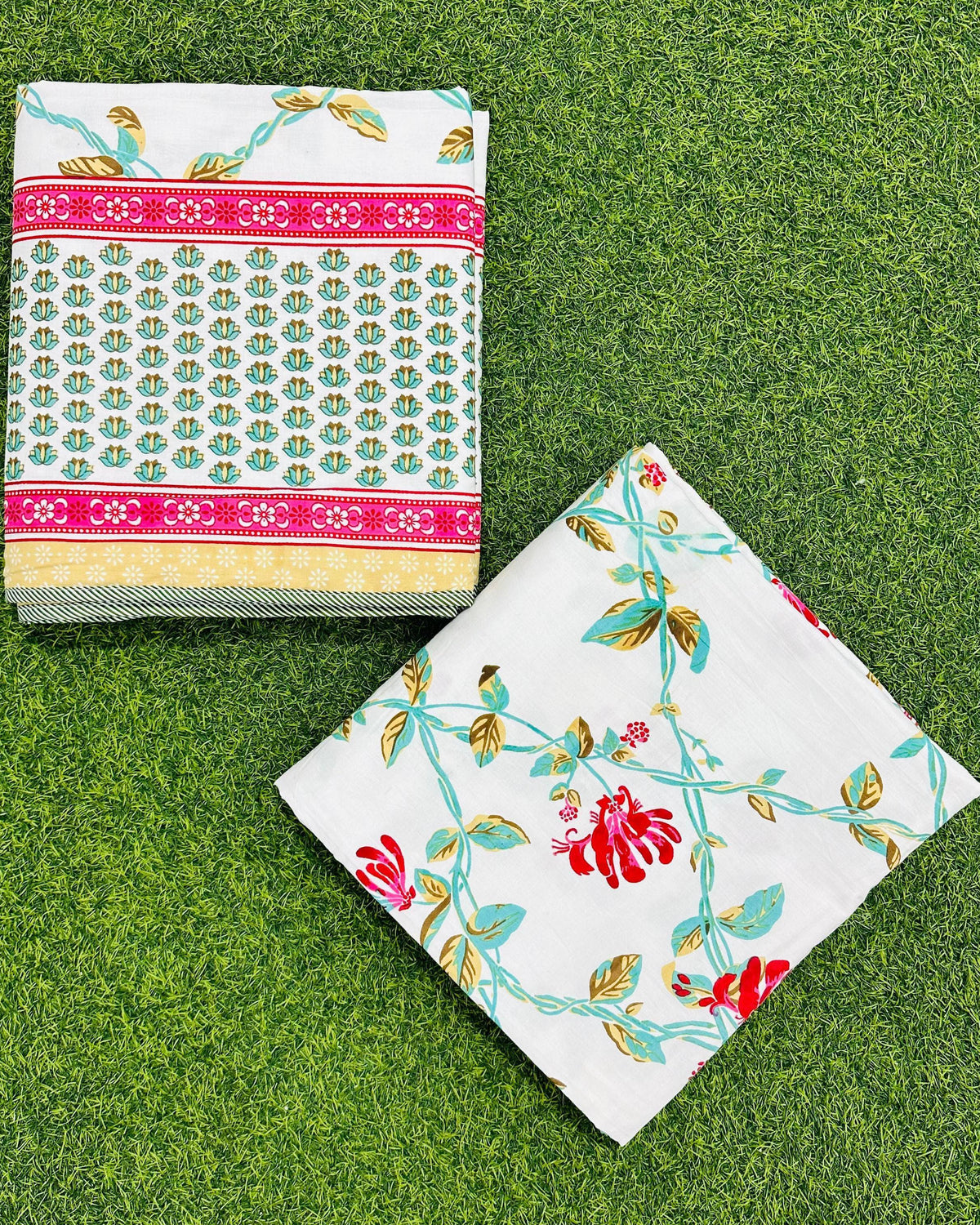 Two folded red floral mulmul dohars showing the printed face and the border band