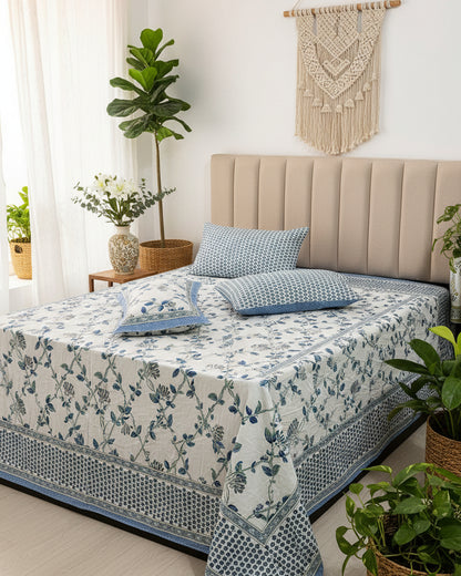 Blue floral cotton bedsheet on a bed with an upholstered headboard and blue dotted pillow covers