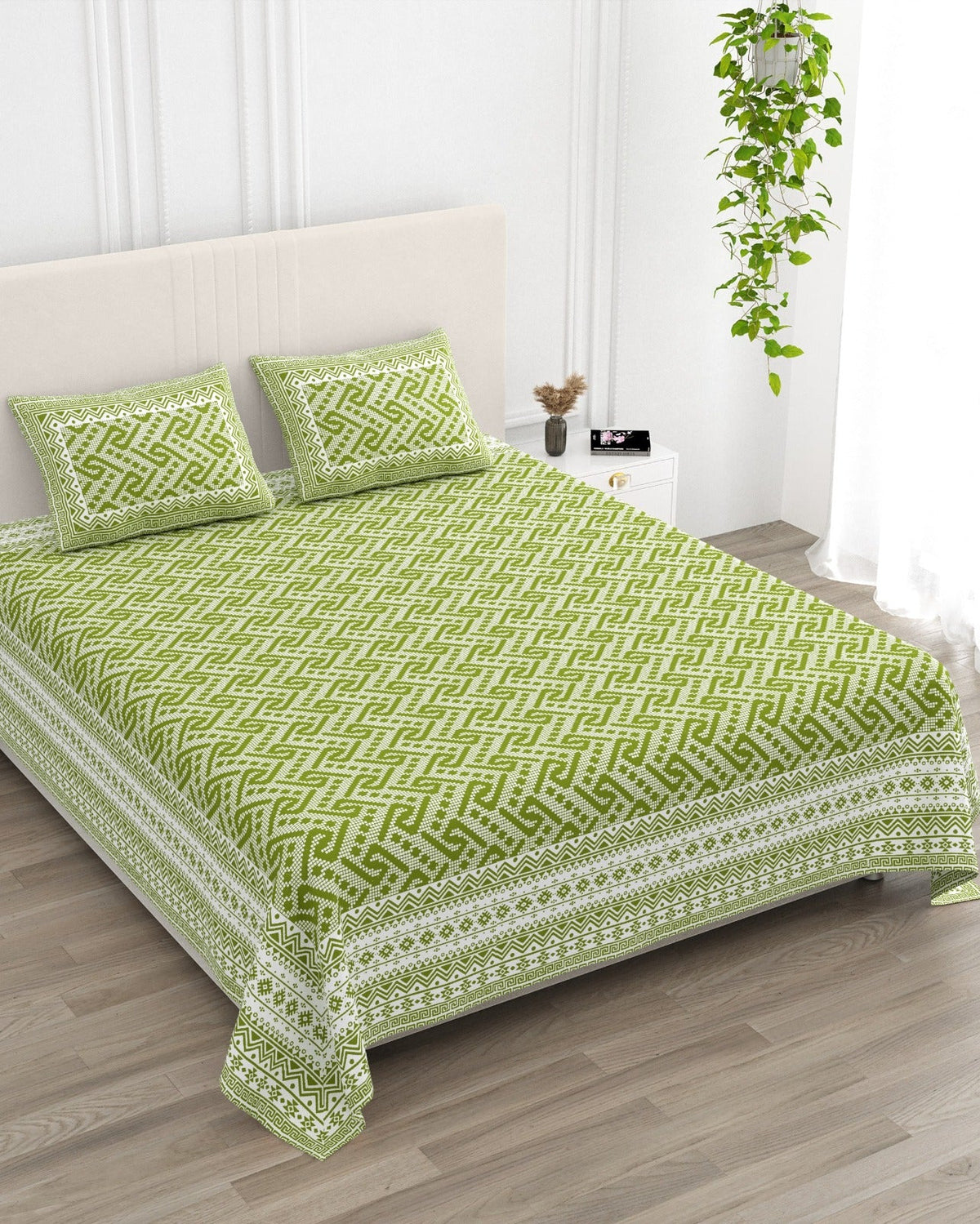 Leher Green bedsheet, leaf-green interlocking key-pattern print, in a studio shot against a cream headboard