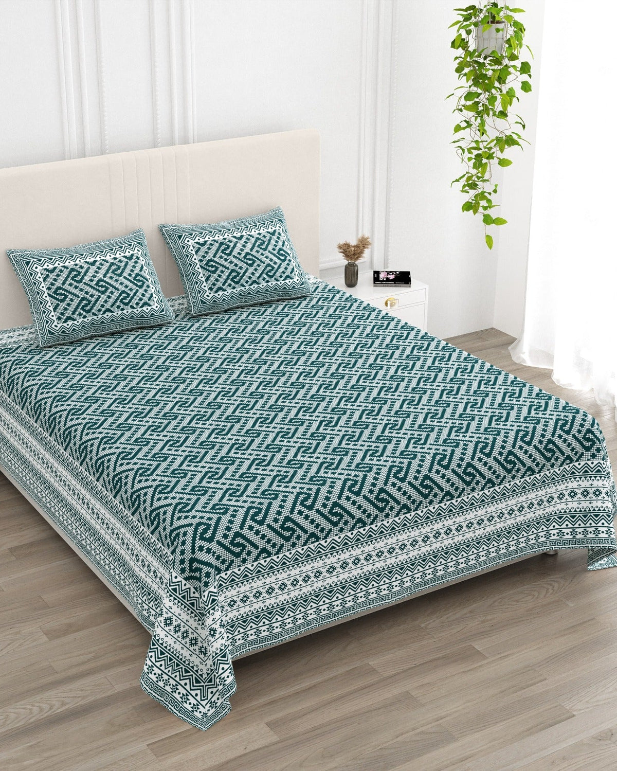 Leher Teal bedsheet, deep teal-green interlocking key-pattern print, in a studio shot against a cream headboard