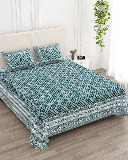 Leher Teal bedsheet, deep teal-green interlocking key-pattern print, in a studio shot against a cream headboard