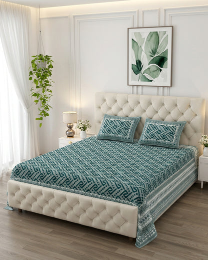 Leher Teal bedsheet, deep teal-green interlocking key-pattern print, on a tufted ivory bed