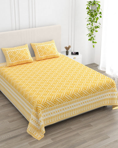 Leher Yellow bedsheet, sunny yellow interlocking key-pattern print, in a studio shot against a cream headboard