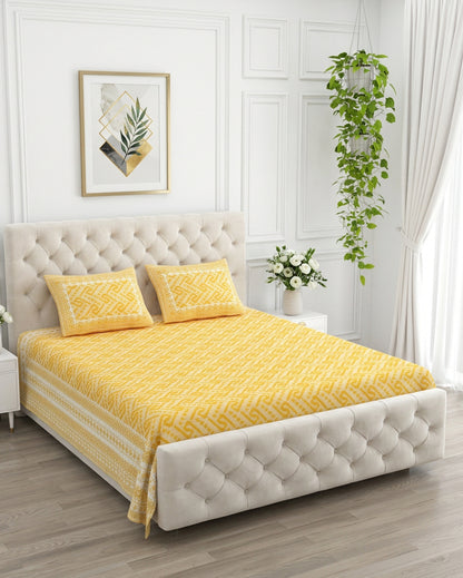 Leher Yellow bedsheet, sunny yellow interlocking key-pattern print, on a tufted ivory bed