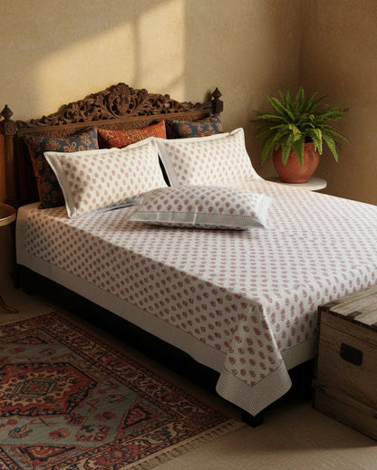 Blush and sage buti hand block percale cotton bedsheet styled on a carved wooden bed