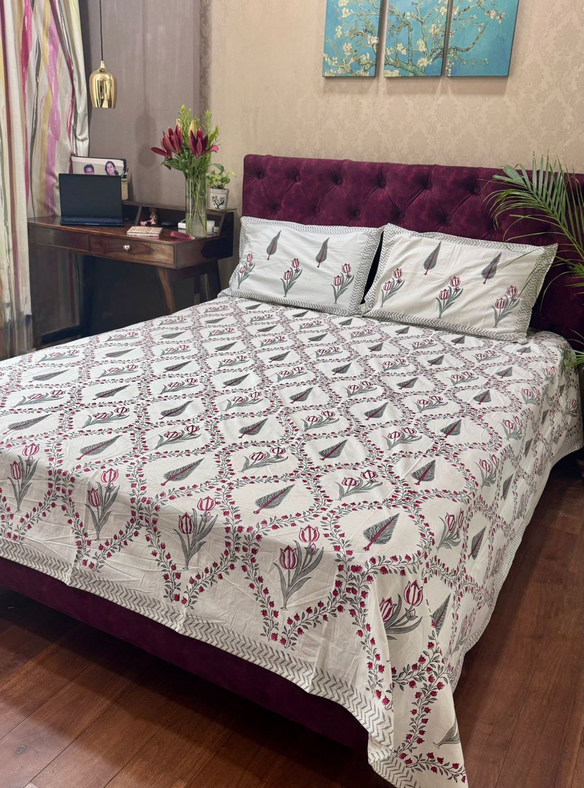 Bed with floral patterned bedspread and pillows in a room setting.