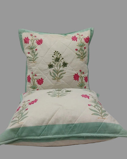 Two Malika blue quilted cushion covers stacked to show the floral print and mint trim