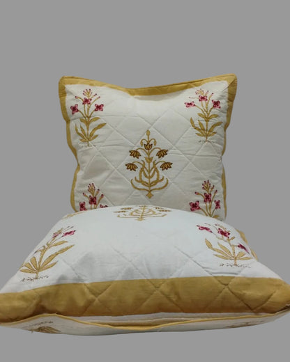 Two Mehek yellow quilted cushion covers stacked to show the floral print and ochre trim