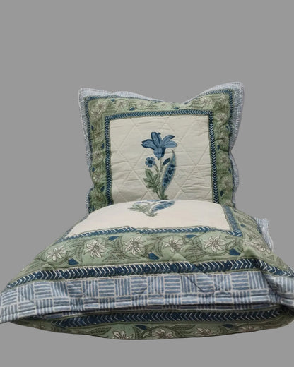 Two Mridula blue quilted cushion covers stacked to show the floral borders and striped reverse