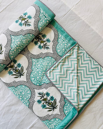 Close-up of mint teal ogee trellis mulmul cotton fabric with a blue floral spray medallion