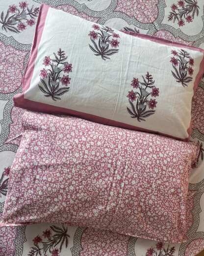 Reversible pillow covers with a pink floral spray on one side and a ditsy pink print on the other