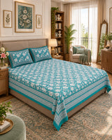 Padmaja Teal Everyday Cotton bedsheet with ivory florals on teal and a striped border, on a bed with a beige headboard