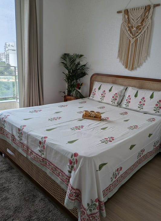Bedroom with a bed covered in a floral-patterned bedsheet, pillows, and a small plant.