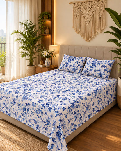 Pallav Blue floral bedsheet on a bed with a light headboard beside a macramé wall hanging
