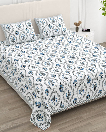 Parijat Blue bedsheet, white floral ogee jaal with blue flowers, in a studio shot against a cream headboard