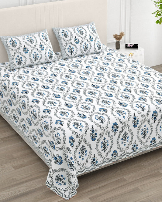 Parijat Blue bedsheet, white floral ogee jaal with blue flowers, in a studio shot against a cream headboard