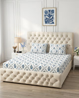 Parijat Blue bedsheet, white floral ogee jaal with blue flowers, on a tufted ivory bed