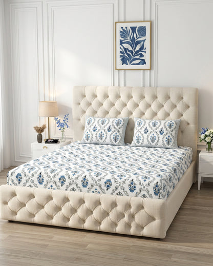 Parijat Blue bedsheet, white floral ogee jaal with blue flowers, on a tufted ivory bed