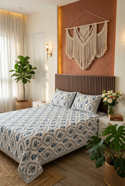 Parijat Blue bedsheet, white floral ogee jaal with blue flowers, on a bed with a slatted wood headboard with macramé