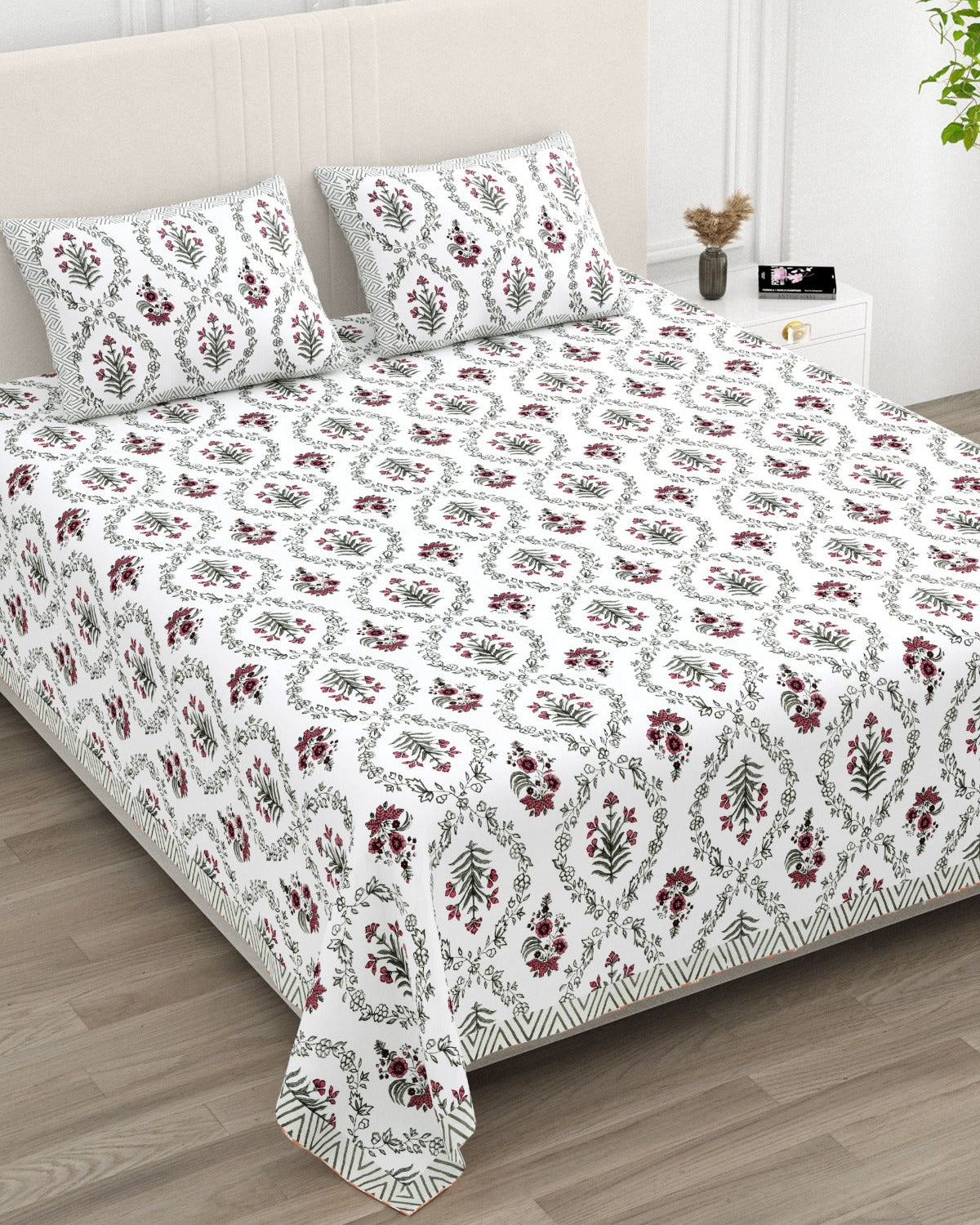 Parijat Pink bedsheet, white floral ogee jaal with berry-rose flowers, in a studio shot against a cream headboard